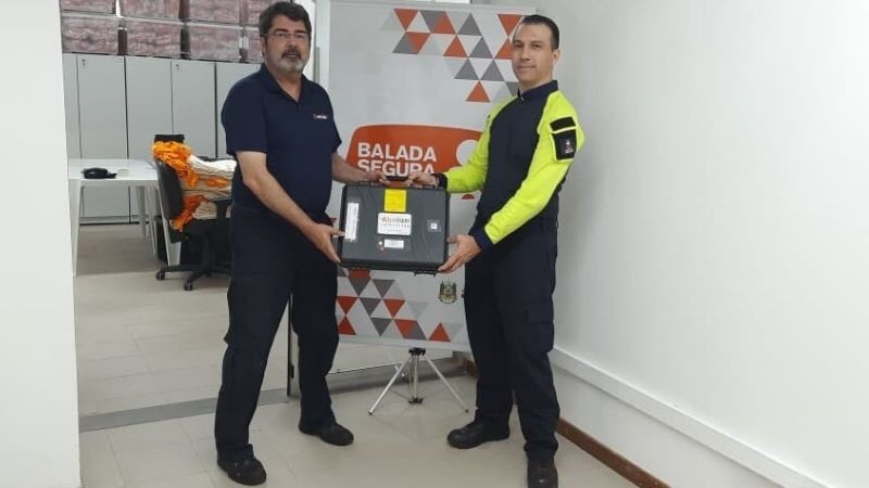 Adriano Saraiva &agrave; esquerda posa entregando uma maleta preta a Alan C&oacute;rdova, na sede da Balada Segura em Porto Alegre